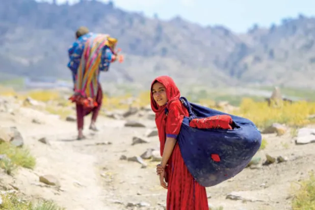 أفغاني وزوجته يحملان أغراضاً جمعاها من بين أنقاض منزلهما المتضرر بالزلزال (إ.ب.أ)