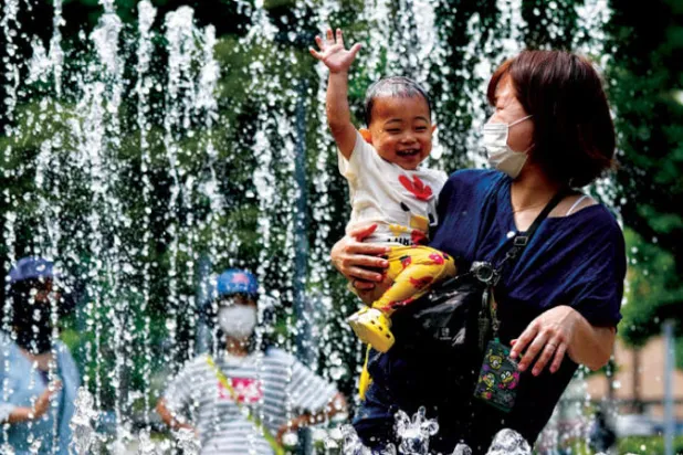 أسر يابانية تلجأ للهو في الحدائق العامة ومياه النافورة هرباً من ارتفاع حرارة الجو (د.ب.أ)