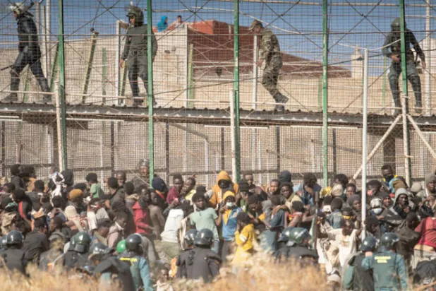قوات أمنية تمنع مهاجرين غير شرعيين من اقتحام السياج الحدودي لمدينة مليلية (أ.ب)