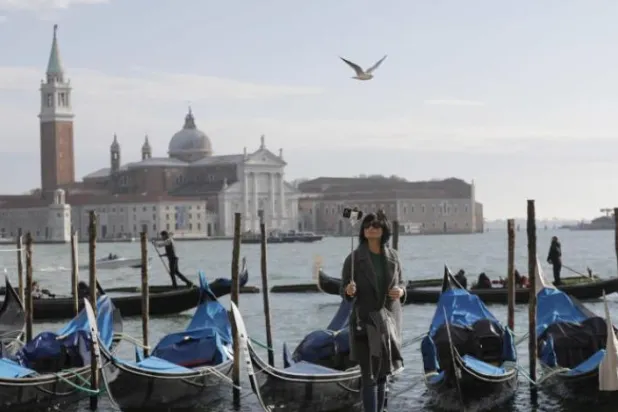 İtalya'nın Venedik kentinde bir turist bir meydanda fotoğraf çekiyor (AP)
