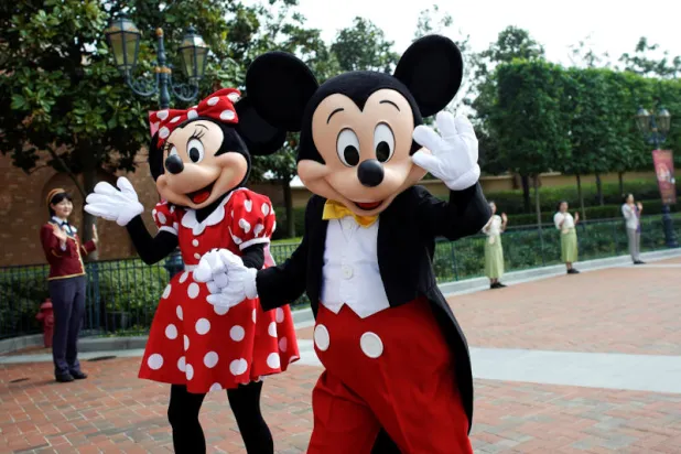 أشخاص يرتدون شخصيتي «ميكي ماوس» و«ميني ماوس» في متنزه «ديزني» بشنغهاي (رويترز)