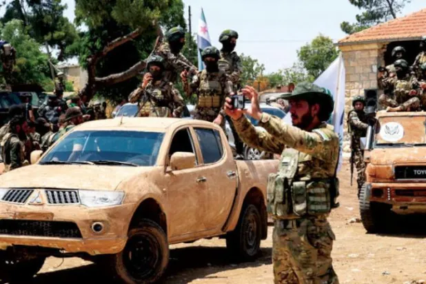 حلب کے شمالی دیہی علاقوں میں فوجی پریڈ کے دوران ترکی کے وفادار شامی جنگجوؤن کو دیکھا جا سکتا ہے (اے ایف پی)