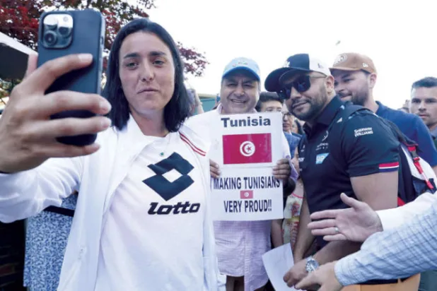 اللاعبة التونسية تلتقط صورة مع بعض المعجبين قبل التدريبات (د.ب.أ)