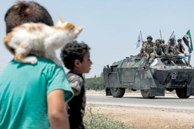 فتيان ينظران إلى مقاتلين معارضين في ريف حلب شمال سوريا في 2 الشهر الحالي (أ.ف.ب)