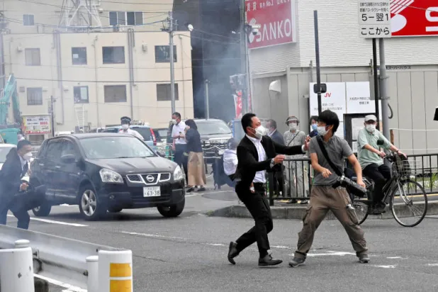 ضابط شرطة يحاول توقيف الرجل الذي أطلق النار على شينزو آبي (رويترز)