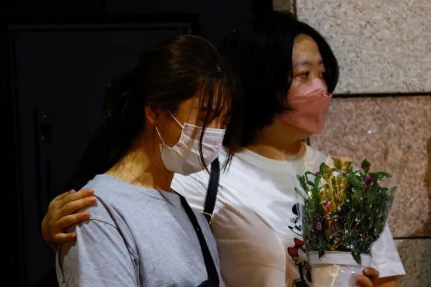 علامات التأثر ظاهرة على سيدتين خلال تجمع لنعي شينزو آبي خارج مقر إقامته في طوكيو (رويترز)