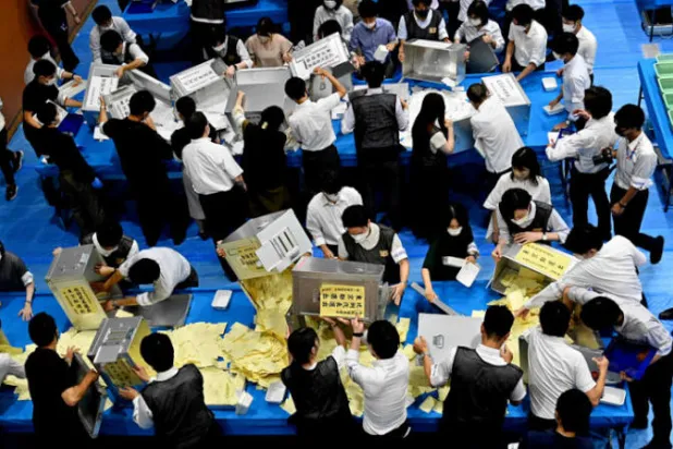 موظفون يفرزون الأصوات يدويا في مكتب اقتراع بطوكيو أمس (أ.ف.ب)