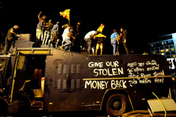 متظاهرون يقفون فوق شاحنة تابعة للشرطة ويطالبون بـ»استرجاع الأموال المنهوبة» في كولومبو، في 9 يوليو (أ.ب)