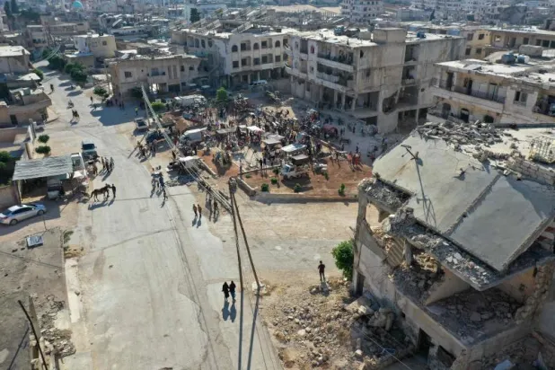 سوريون يؤدون صلاة عيد الأضحى بالقرب من مبانٍ مدمرة في مدينة بنش بمحافظة إدلب شمال غربي البلاد (أ.ف.ب)