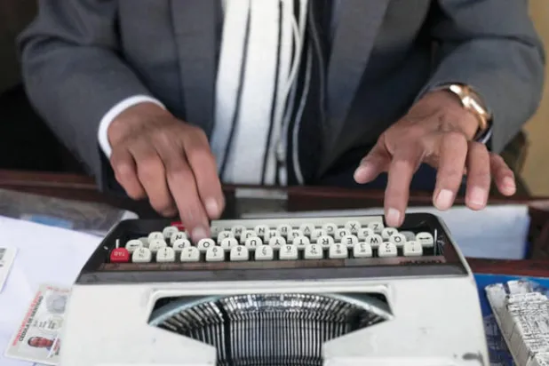 يجلس الطابعون في الشارع لملء النماذج وحتى كتابة الرسائل الشخصية لعملائهم في بوليفيا (أ.ف.ب)