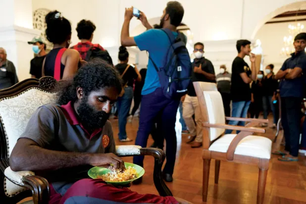 أحد المتظاهرين يتناول الطعام داخل مقر سكن رئيس الوزراء الذي اقتحمه المتظاهرون أيضاً (أ.ب)
