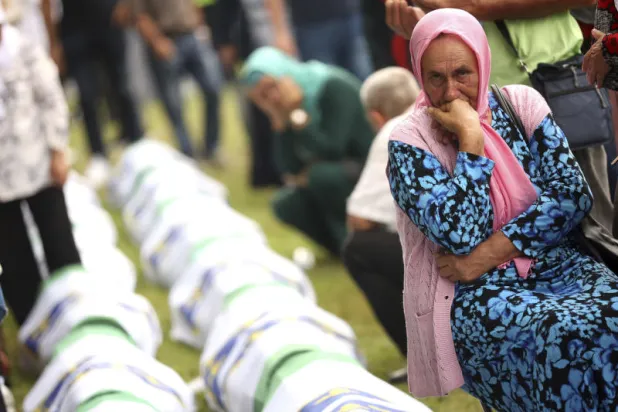 امرأة بوسنية تبكي بجوار التابوت الذي يحتوي رفات أحد أفراد عائلتها الذي كان من بين ضحايا الإبادة (أ.ب)