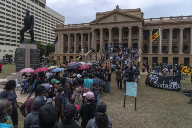 مواطنون ينتظرون في طوابير للدخول إلى مكتب الرئيس السريلانكي بعدما اقتحمه متظاهرون (أ.ب)