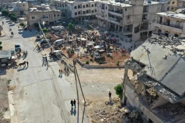 Suriyeliler, ülkenin kuzeybatısındaki İdlib vilayetine bağlı Binniş şehrinde yıkılan binaların yakınında Kurban Bayramı namazını kılıyor (AFP)