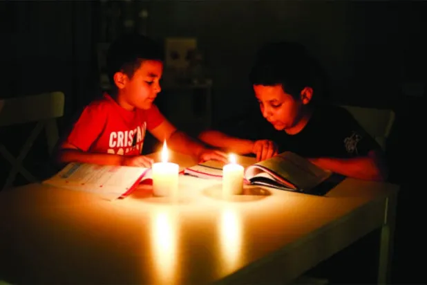 الدراسة على ضوء الشموع نتيجة انقطاع الكهرباء في طرابلس في 30 يونيو الماضي (رويترز)