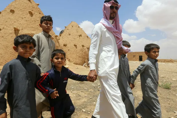 Abdulaziz al-Oqab walks with his nephews who were orphaned when a landmine exploded under a pick-up truck, claiming the lives of 21 family members. AFP