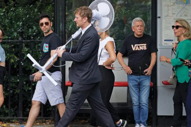 رجل يحمل مروحة كبيرة يسير في ويستمنستر (د.ب.أ)