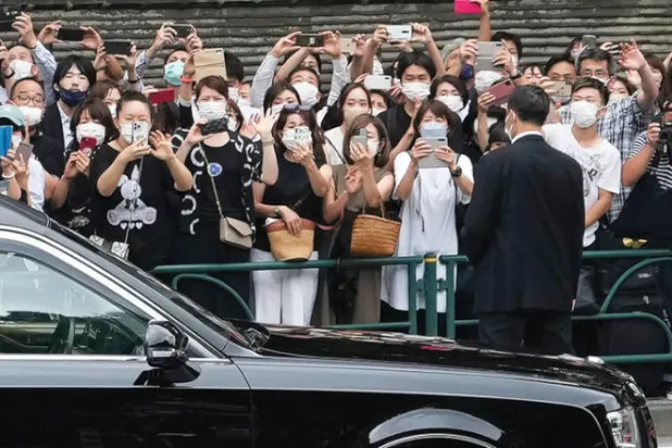 يابانيون يتابعون السيارة التي نقلت نعش شينزو آبي في طوكيو أمس (أ ب)