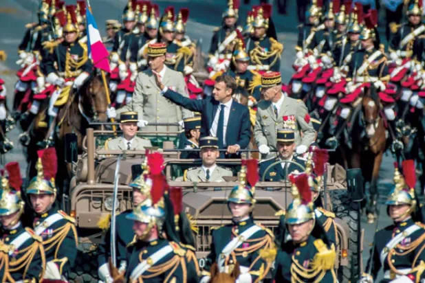 ماكرون وبجانبه رئيس الأركان الفرنسي يحيي الحضور في مستهل العرض العسكري بمناسبة العيد الوطني في باريس أمس (إ.ب.أ)