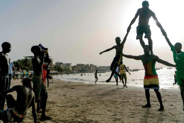 ماليك يؤدي حركات بهلوانية على شاطئ نغور في دكار بالسنغال (إ.ف.ب)