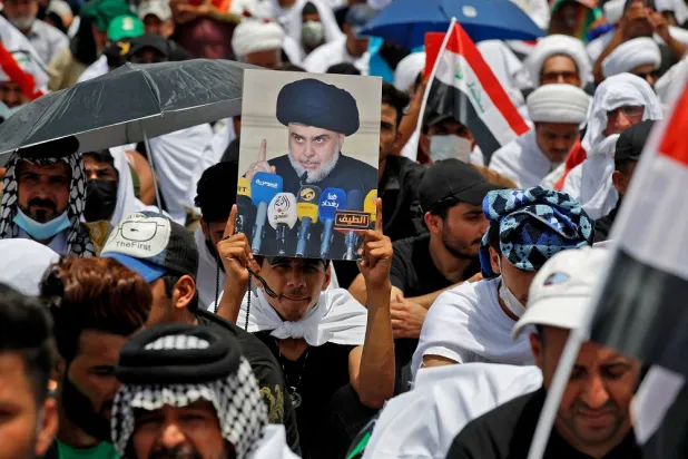 A supporter of Iraqi Shiite cleric Moqtada al-Sadr lifts a placard depicting him during a a collective Friday prayer in Sadr City, east of Baghdad on July 15, 2022. (AFP)