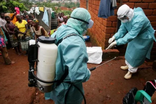 مسؤولون صحيون خارج منزل مريض بفيروس ماربورغ أثناء تفشي المرض في أنغولا عام 2005 (رويترز)