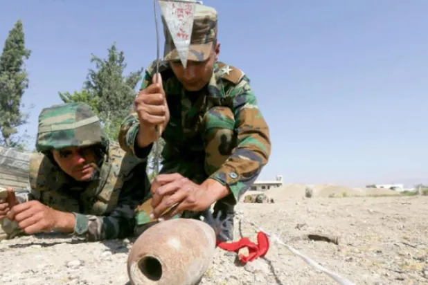 Two Syrian soldiers conduct a demining exercise near Damascus on June 19. (AFP)
