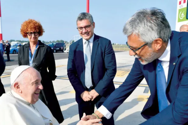 البابا يصافح مسؤولاً في مطار روما الدولي أمس (رويترز)