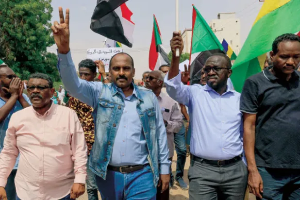 العضو السابق في مجلس السيادة السوداني محمد الفكي سليمان ملوحا بشارة النصر ضمن موكب للمعارضة في الخرطوم (رويترز)