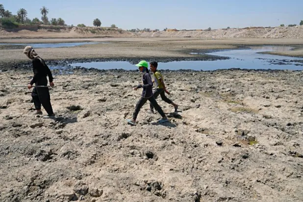 عراقيون يعبرون أمام نهر ديالى الذي تراجع منسوبه بشكل كبير (أ.ب)