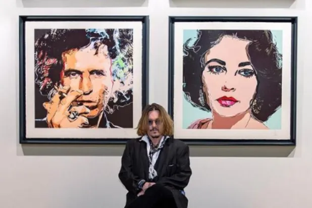 الممثل الأميركي جوني ديب يجلس أمام لوحتين فنيتين من أعماله (إنستغرام)