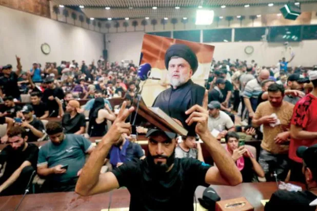کل بغداد کے گرین زون میں الصدر کے ایک حامی کو پارلیمنٹ کے ہیڈ کوارٹر پر دھاوا بولنے کے بعد ان کی تصویر اٹھائے ہوئے دیکھا جا سکتا ہے (اے ایف پی)