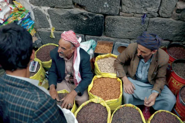 بائعان يستقبلان زبوناً في سوق وسط صنعاء (إ.ب.أ)