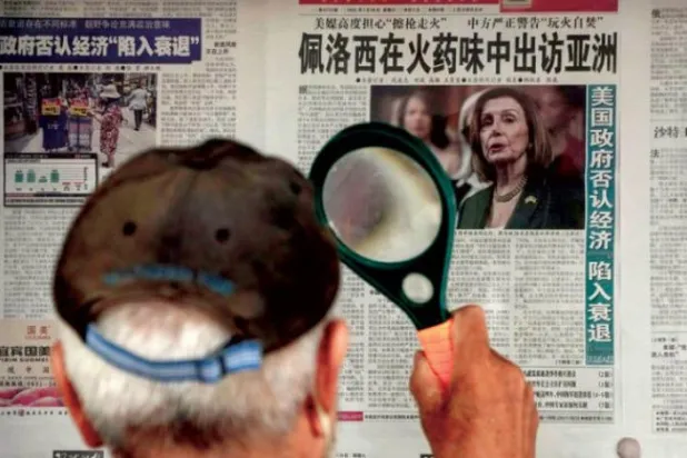Pekin'deki bir gazete bayisinde Pelosi'nin Asya ziyaretine dair haberi okuyan bir adam (AP)