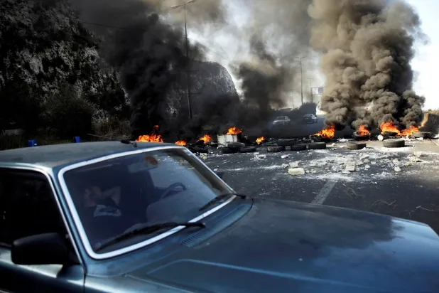 A man sleeps in a car next to burning tires barricading the highway during ongoing anti-government protests at Nahr El Kalb, Lebanon November 13, 2019. (Reuters)