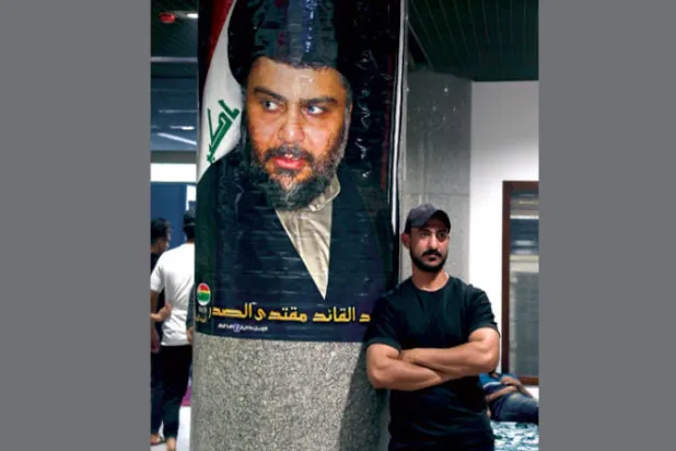 أحد مناصري مقتدى الصدر أمام صورة له في البرلمان العراقي (إ.ب.أ)