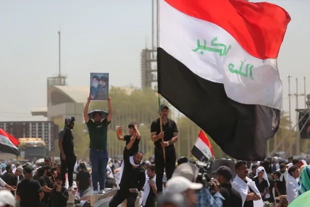 Followers of Shiite cleric Moqtada al-Sadr hold posters with his image during an open-air Friday prayers at Grand Festivities Square within the Green Zone, in Baghdad, Iraq, Friday, Aug. 5, 2022. (AP)