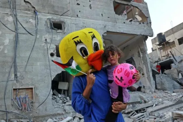 
یک مرد فلسطینی دختری را در میان ویرانی‌هایی که در خانه ای در رفح در نتیجه بمباران اسرائیل رخ داد حمل می‌کند (AFP)