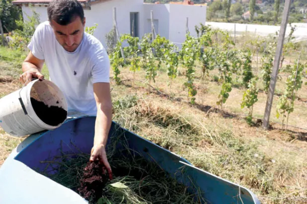 ألبان كاكالي يخلط تفل القهوة مع القش لإعداد السماد في مزرعته (أ.ف.ب)