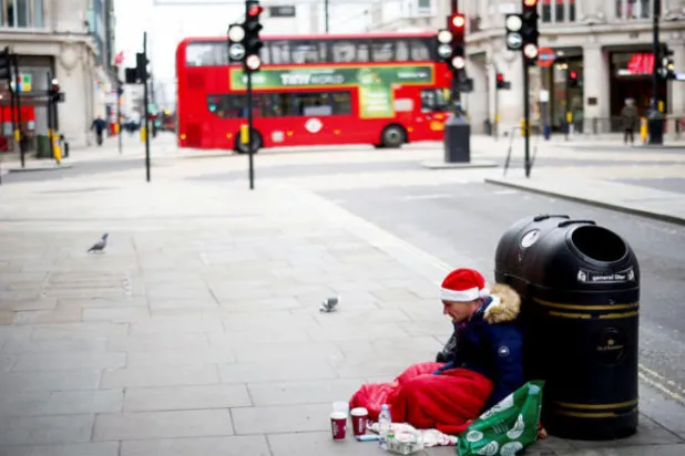 رجل بلا مأوى يجلس في شارع أكسفورد بالعاصمة البريطانية لندن (رويترز)