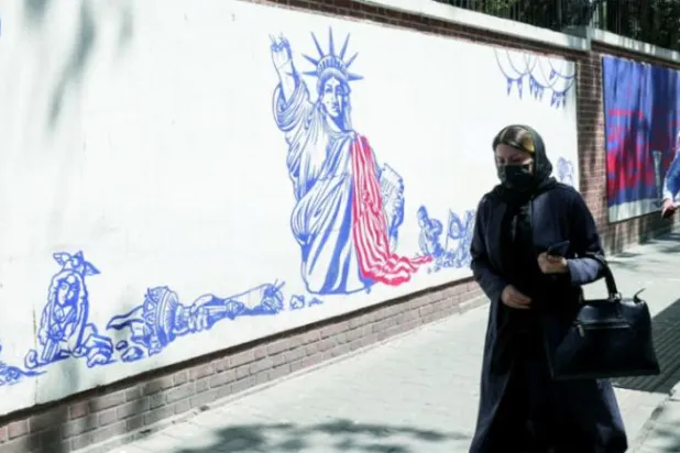 ایک ایرانی خاتون گزشتہ منگل کو تہران میں سابق امریکی سفارت خانے کی دیوار پر امریکہ مخالف پوسٹ کے سامنے سے گزر رہی ہے (رائٹرز)