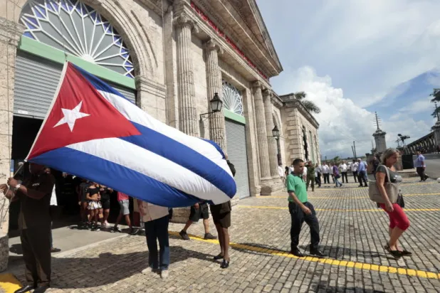 أفراد يحملون علم كوبا في مدينة ماتانزاس الكوبية (إ.ب.أ)