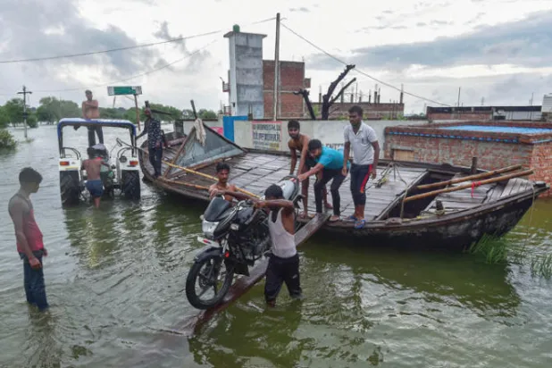 قرويون يستخدمون قارباً صغيراً هرباً من الفيضانات التي غطت بيوتهم ومزارعهم في شرق الهند (أ.ف.ب)