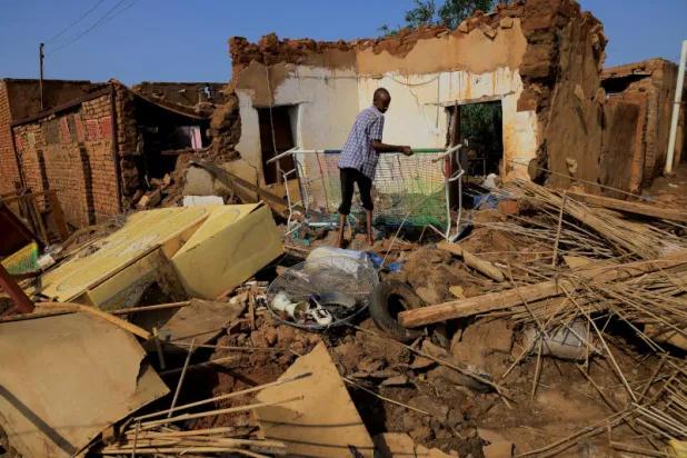 رجل يجمع متعلقاته بعد تعرض منزله لأضرار بسبب المياه أثناء الفيضانات في محلية المناقل بولاية الجزيرة (رويترز)