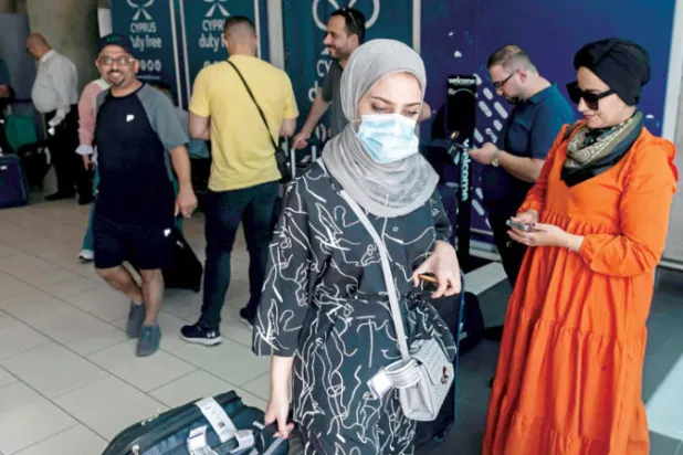 فلسطينيون في مطار لارنكا بعد وصولهم على متن أول رحلة جوية من مطار رامون الاثنين (إ.ف.ب)