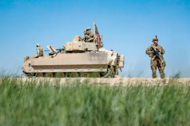 Geçtiğimiz nisan ayında Suriye'nin kuzeydoğusunda Bradley zırhlı aracının yanında duran bir Amerikan askeri. (AFP) 