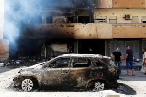 لڑائیوں کے اگلے دن، کل طرابلس میں تباہ شدہ کار اور جلتی ہوئی عمارت (رائٹرز)