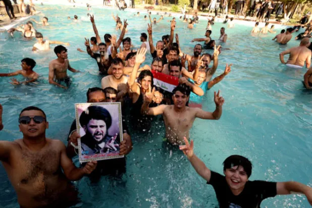 مناصرو الصدر يرفعون صورته في مسبح القصر الجمهوري في بغداد أمس (رويترز)