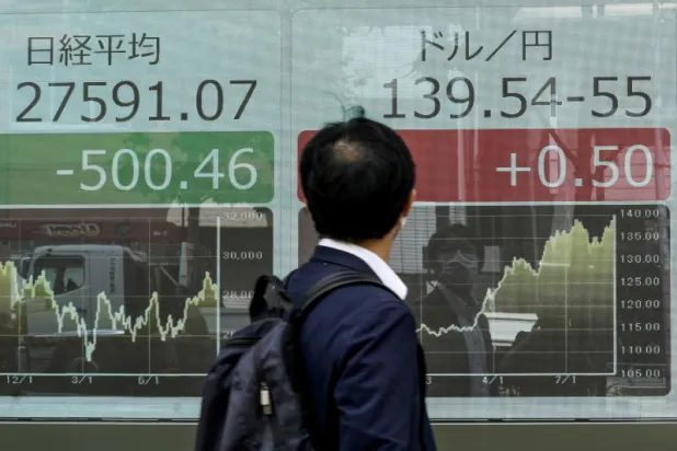 رجل يتفقد سعر الصرف بين الين الياباني والدولار الأميركي في طوكيو (إ.ب.أ)