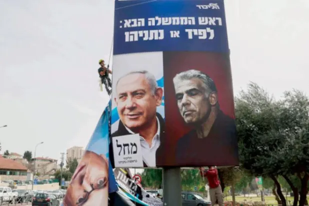Mart 2021’de İsrail Başbakanı Binyamin Netanyahu (solda) ve rakibi Yeş Atid Partisi lideri Yair Lapid'in yer aldığı seçim afişi (AFP)